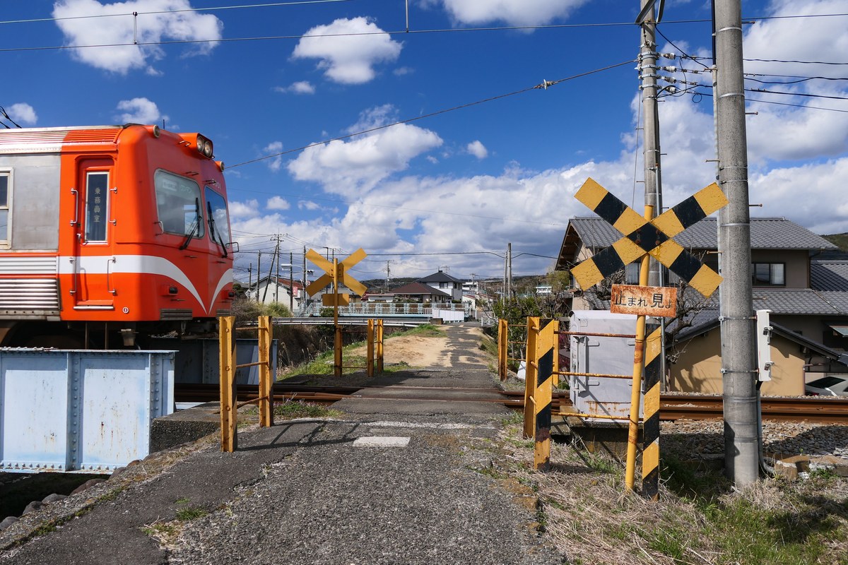 踏切のそばを走るオレンジ色の電車