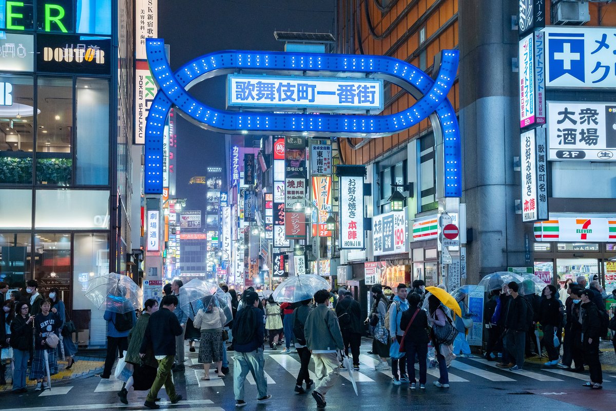 夜の歌舞伎町一番街の入り口と、道を歩く大勢の人(東京・新宿)